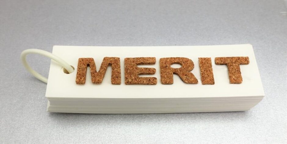 コルク素材で『MERIT』と書かれた単語帳がグレーの机上に置かれている様子